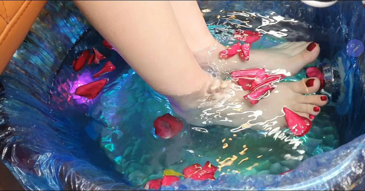 Rose petal foot spa — feet soaking in iridescent blue water with red rose petals