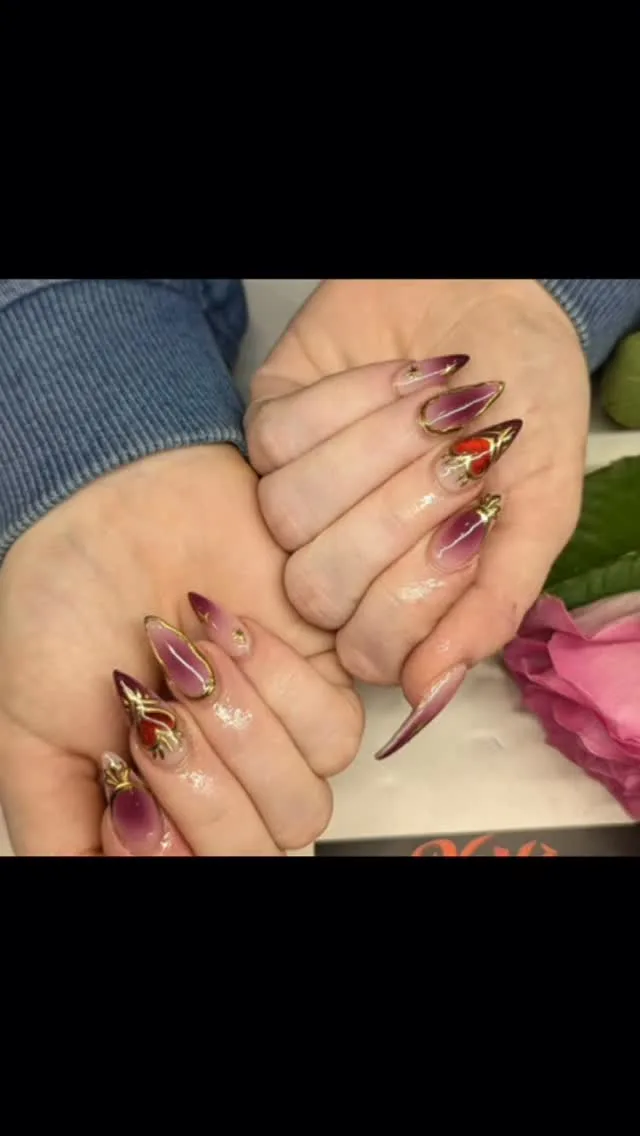 Burgundy and gold gem almond nails with red nail art, two hands beside a pink rose